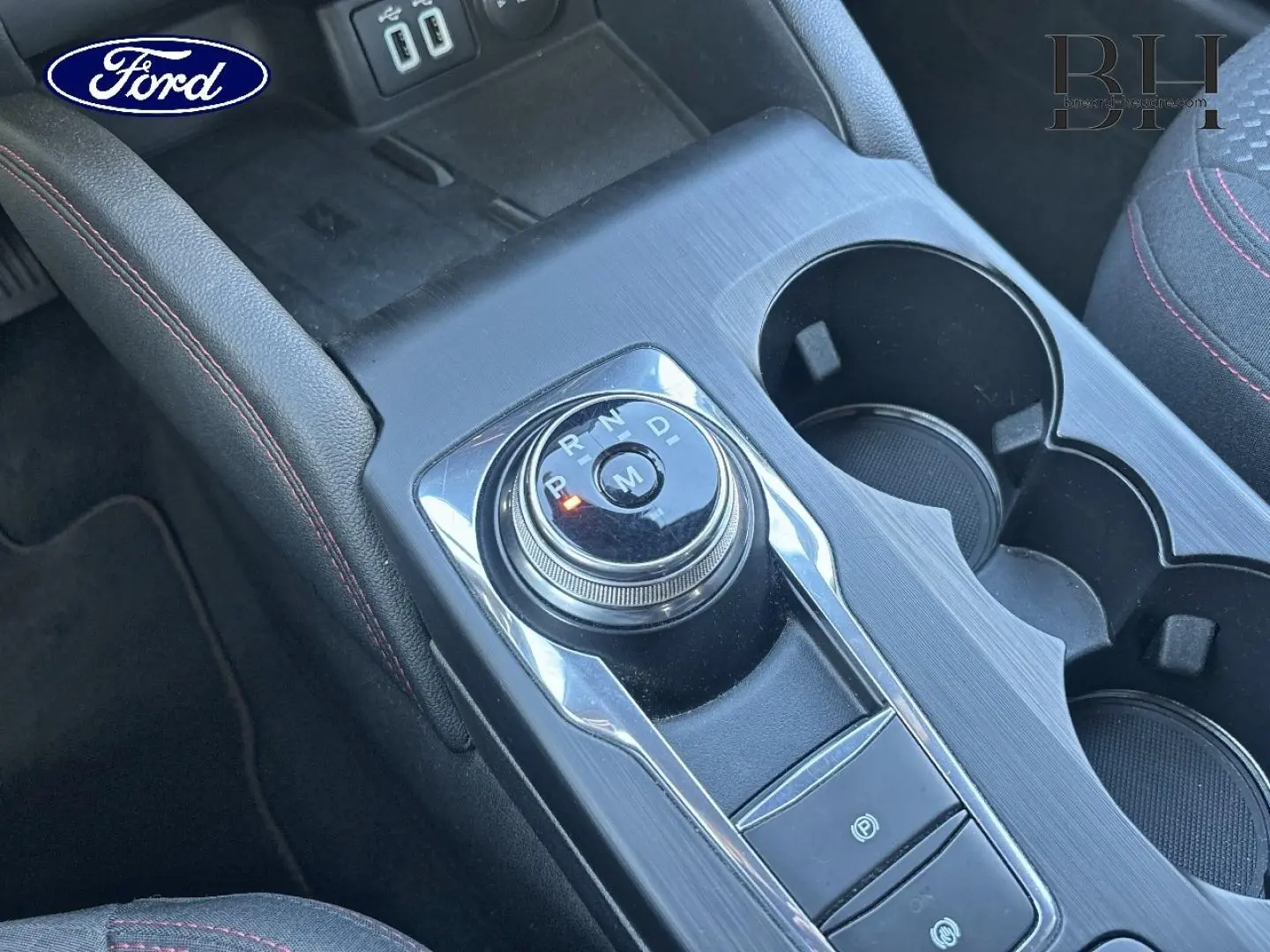 Vue rapprochée de la console centrale du Ford Kuga 2021 avec molette de boîte auto, finition noire et coutures rouges.