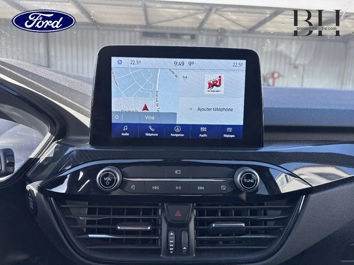 Vue rapprochée de la console centrale du Ford Kuga 2021 avec écran tactile affichant la navigation et commandes audio.