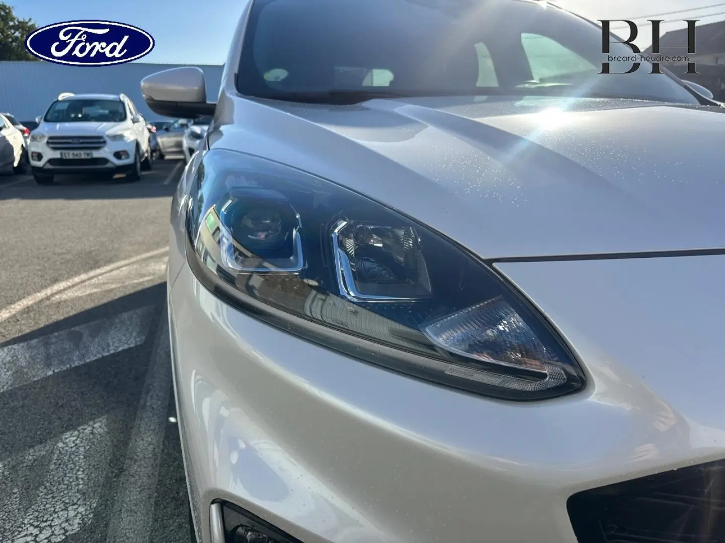 Gros plan sur le phare avant gauche d’un Ford Kuga blanc Premium Platinum sous lumière naturelle.