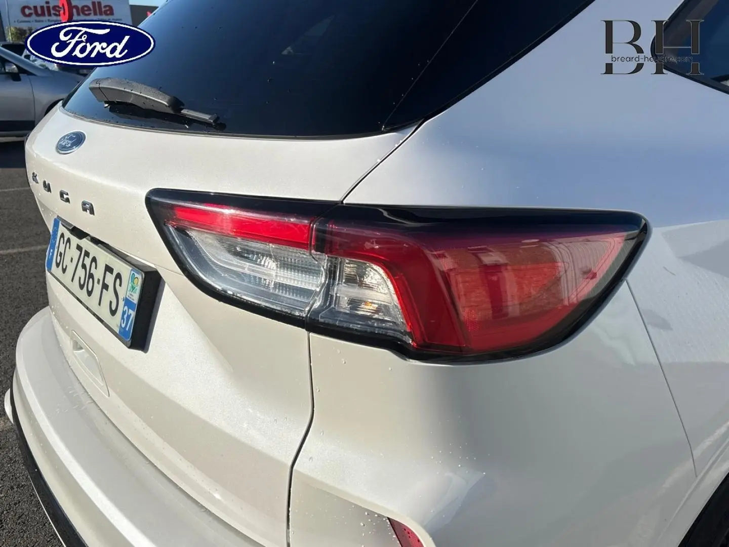 Vue 3/4 arrière droite d'un Ford Kuga blanc Premium Platinum avec feux arrière LED et hayon mains libres.