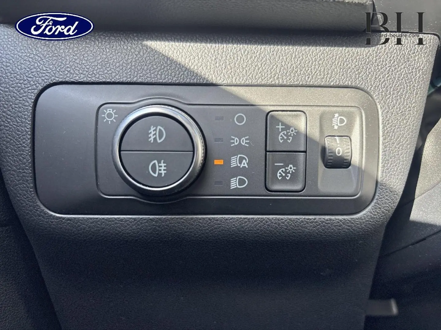Gros plan sur les commandes d’éclairage du tableau de bord du Ford Kuga 1.5 EcoBlue blanc, avec bouton rotatif et réglages LED.