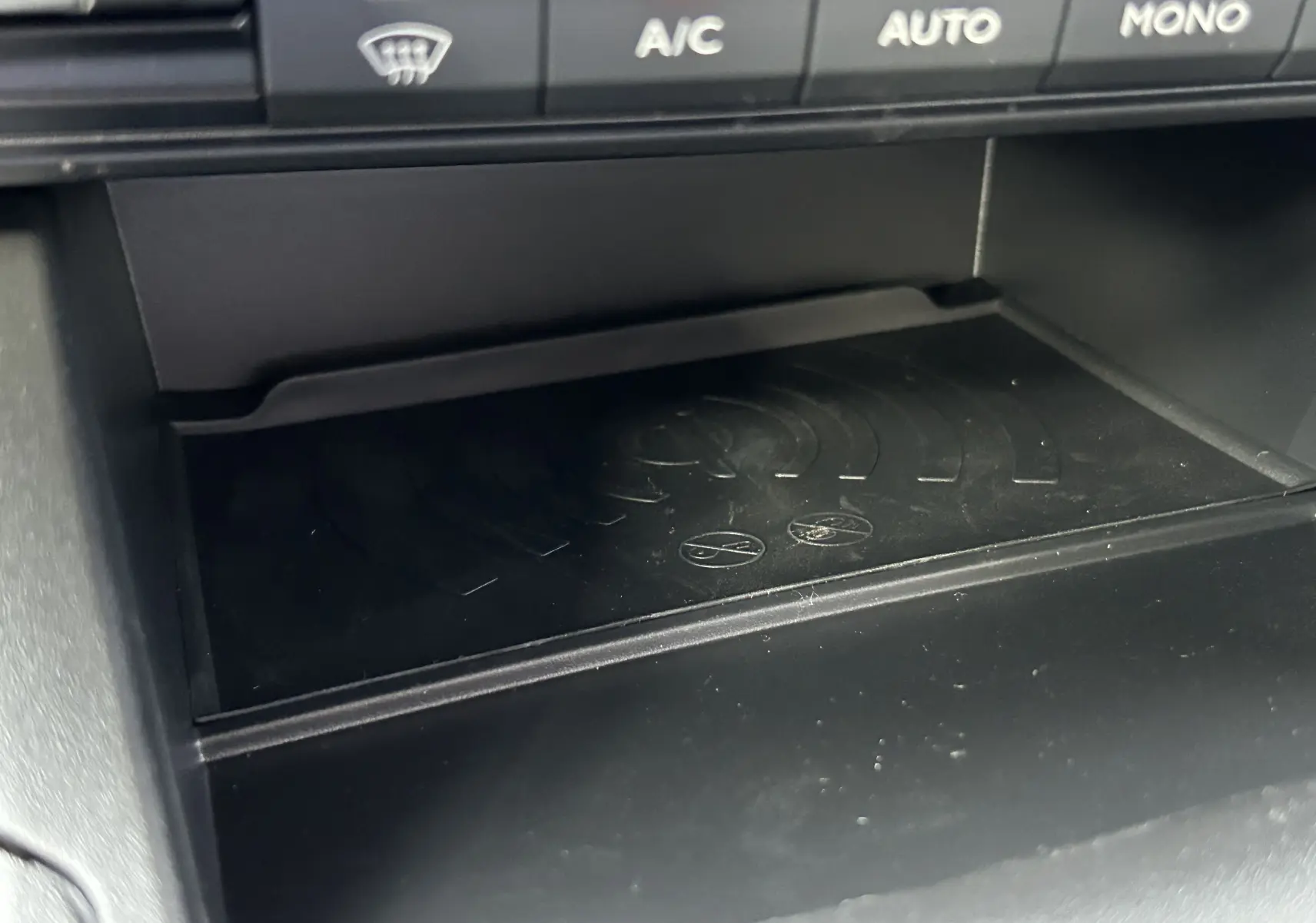 Gros plan sur le compartiment de recharge sans fil sous les commandes de climatisation du Peugeot Partner Fourgon blanc 2025.