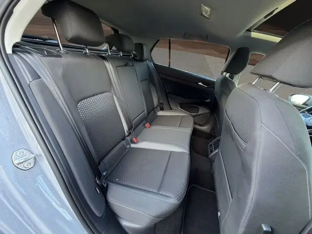 Vue intérieure arrière côté gauche de la Volkswagen Golf VIII gris lunaire, montrant les sièges arrière en tissu noir et vitres surteintées.