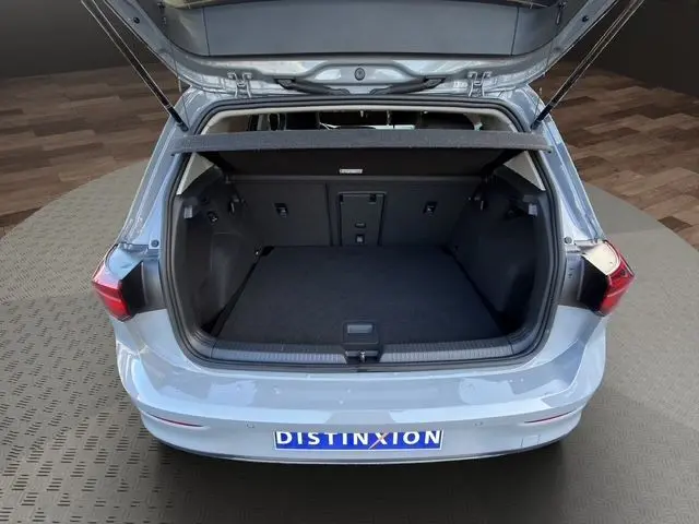 Coffre ouvert vu de l'arrière d'une Volkswagen Golf VIII gris lunaire, montrant l'espace de chargement vide.