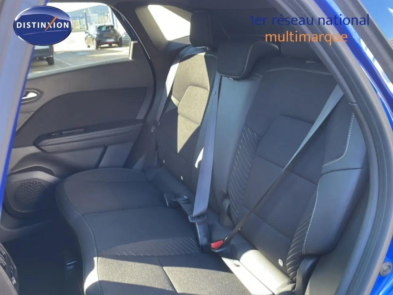 Vue intérieure sur les sièges arrière noirs d’un Renault Symbioz bleu Iron Metal, avec ceinture de sécurité attachée côté droit.