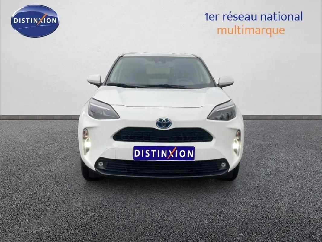 Vue frontale d'une Toyota Yaris Cross Hybrid blanche de 2024 avec phares allumés et calandre noire.