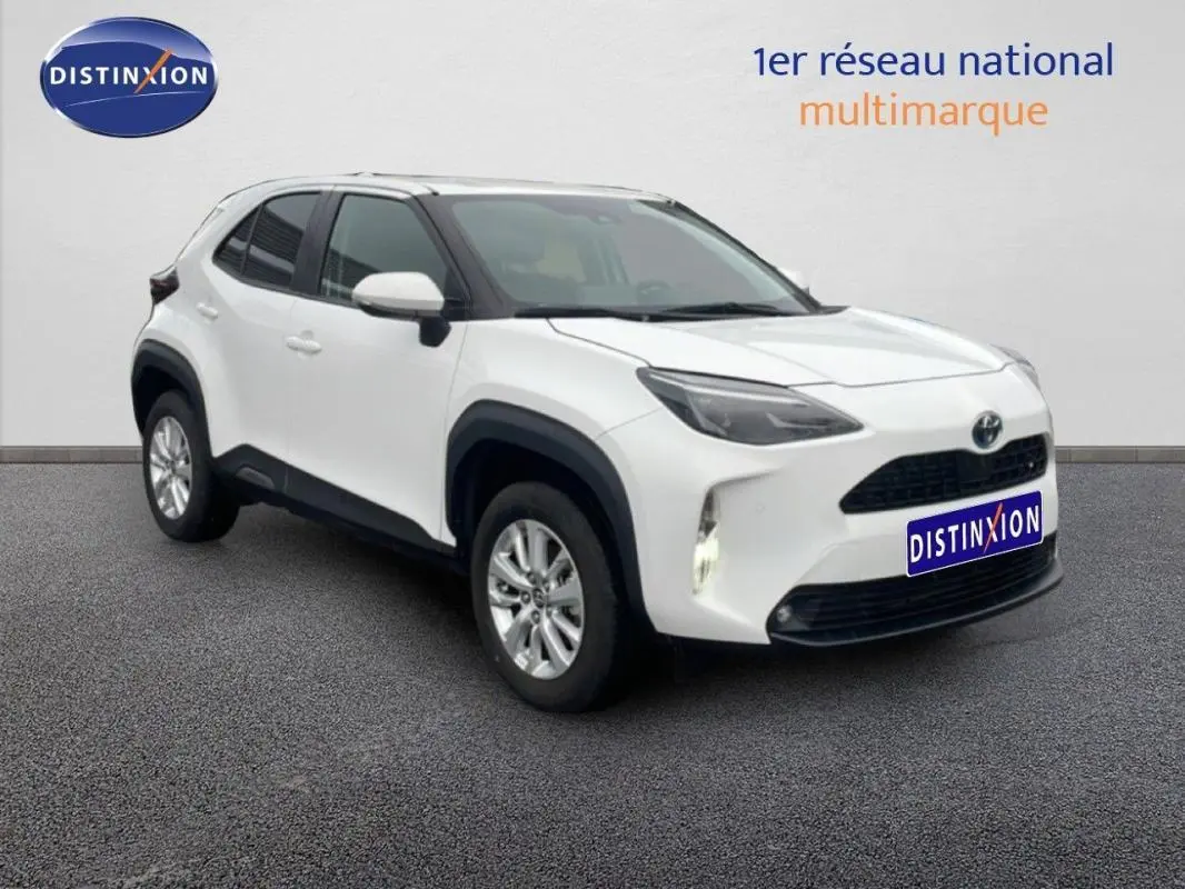 Toyota Yaris Cross Hybrid blanc vue 3/4 avant droit avec jantes aluminium et phares allumés.