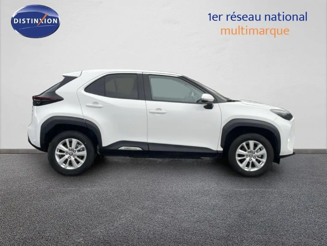 Profil droit d'un Toyota Yaris Cross blanc 2024 hybride avec jantes aluminium 16 pouces et protections noires.