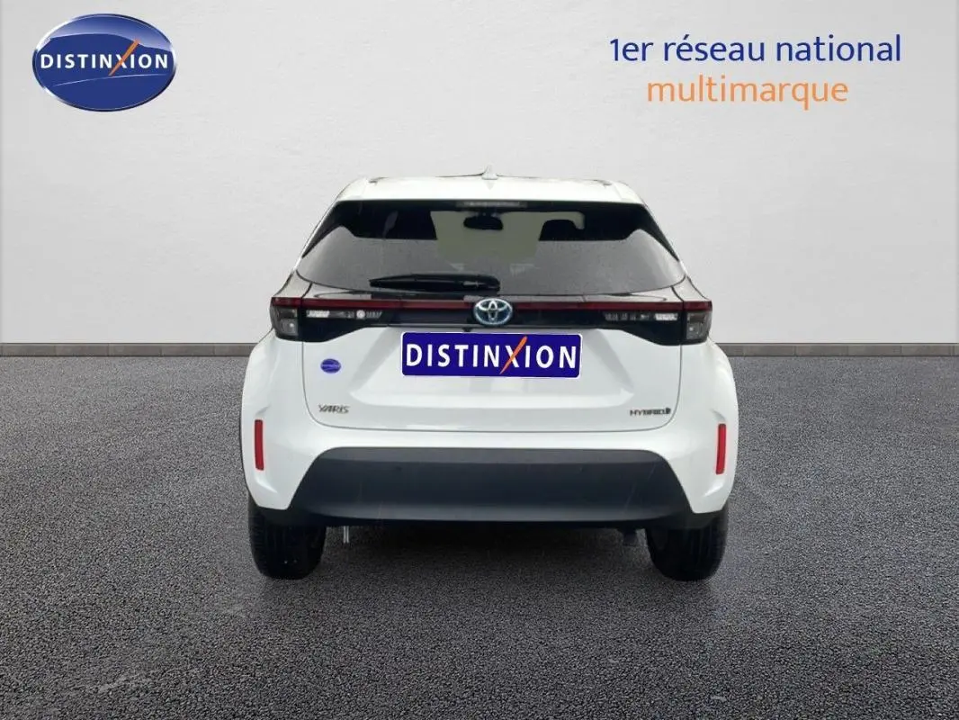 Vue arrière d'une Toyota Yaris Cross Hybrid blanche de 2024, avec feux arrière noirs et logo Toyota visible.