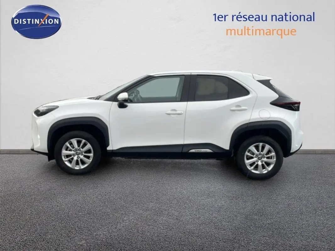 Profil droit de la Toyota Yaris Cross Hybrid blanche 2024 avec jantes aluminium 16 pouces et protections noires contrastées.