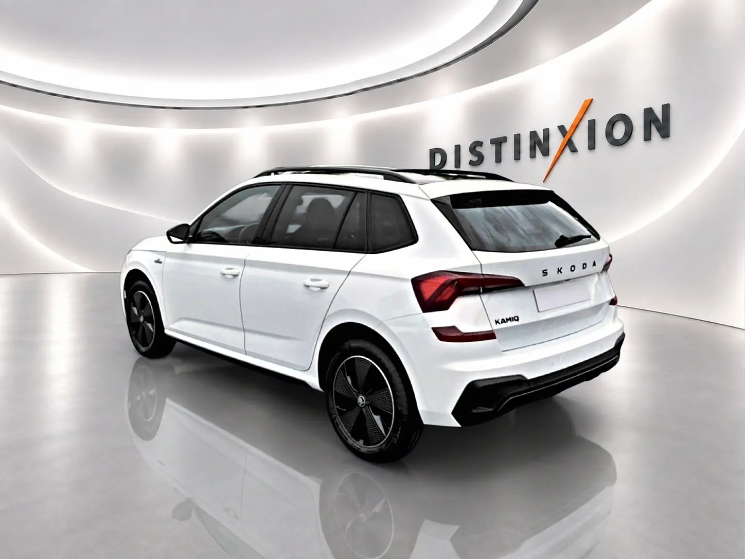 Vue 3/4 arrière droite d'un Skoda Kamiq blanc nacré avec jantes noires et toit panoramique en studio lumineux.