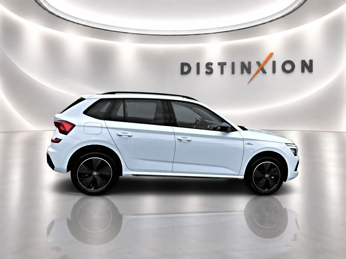 Vue latérale droite d'un Skoda Kamiq blanc nacré avec jantes noires et toit panoramique en studio lumineux.
