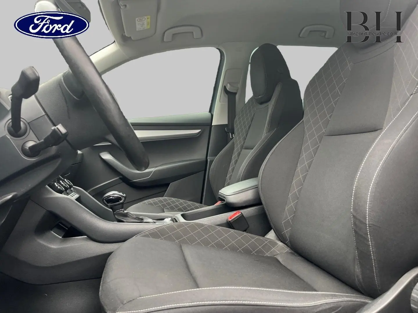 Vue intérieure côté conducteur du Skoda Karoq 1.6 TDI 2020, sièges tissu gris avec surpiqûres croisées.