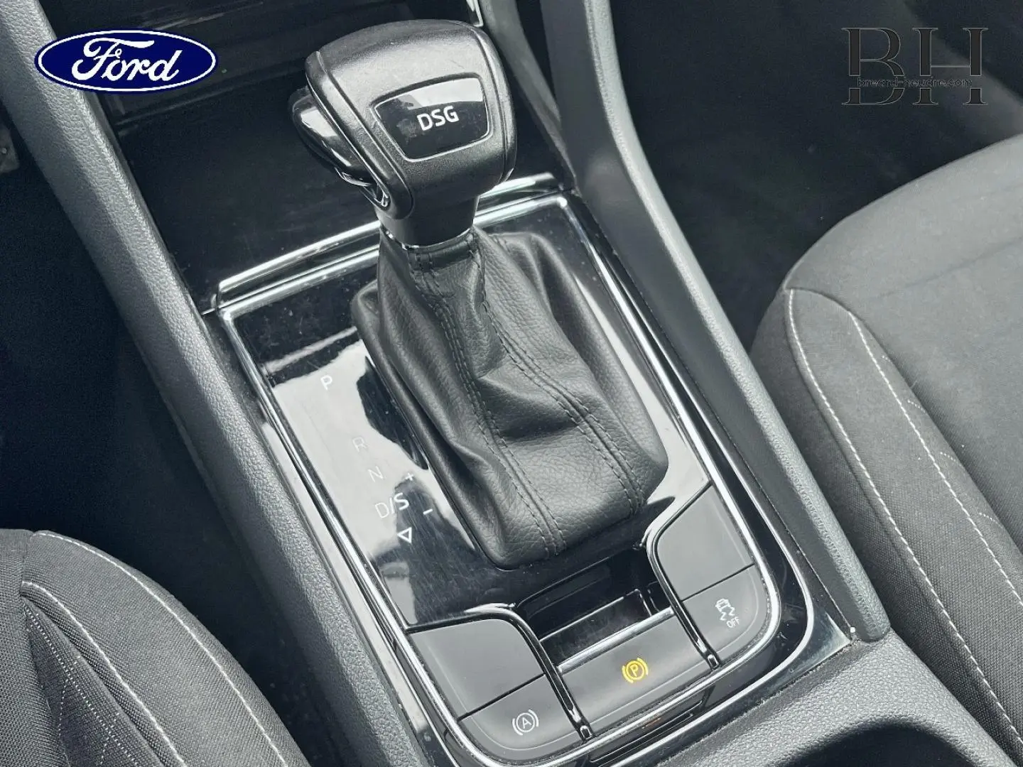 Gros plan sur le levier de vitesses DSG noir et cuir dans l'habitacle d'un Skoda Karoq gris Business, console centrale visible.