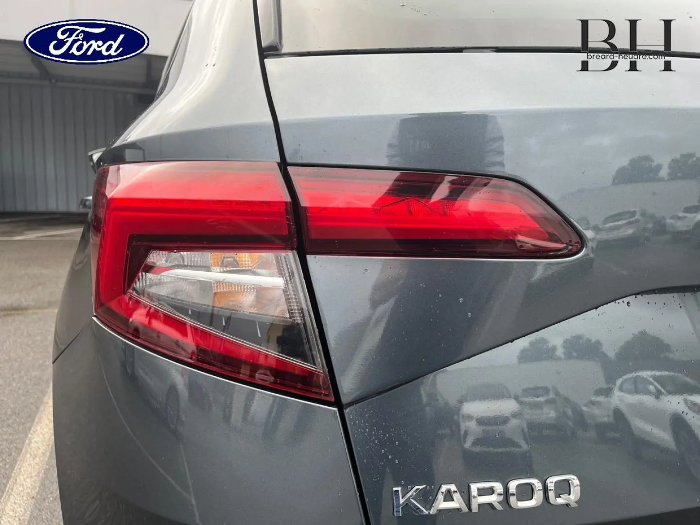 Gros plan sur le feu arrière gauche d’un Skoda Karoq gris Business, soulignant la finition et les lignes du coffre.