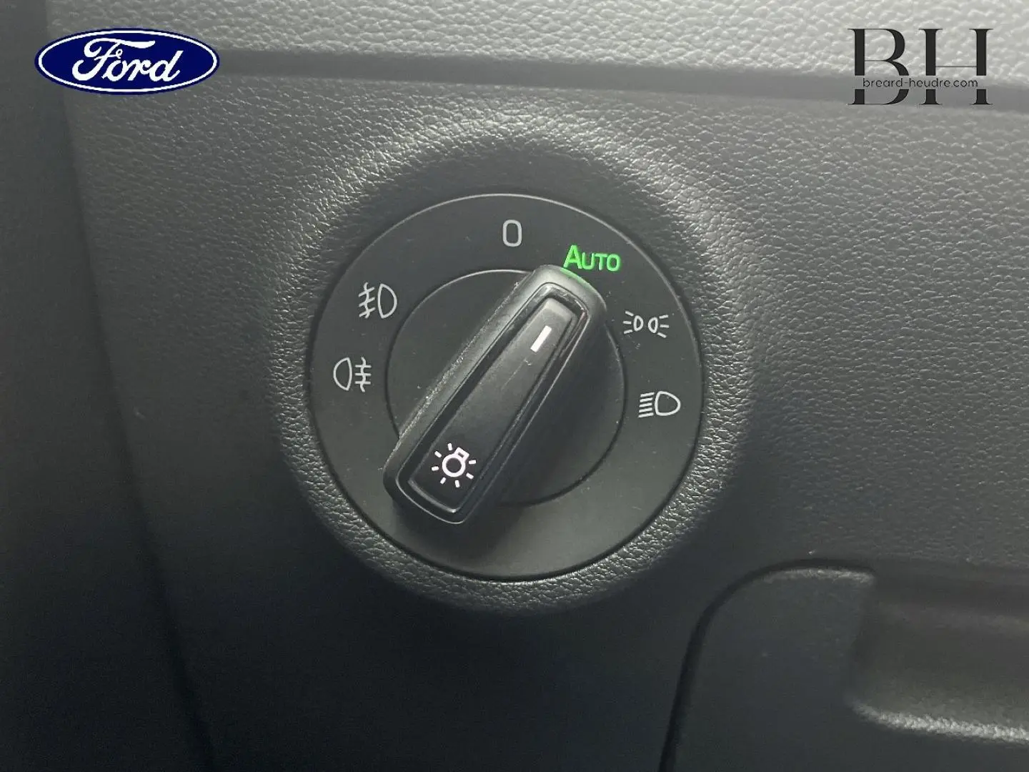 Gros plan sur le sélecteur de feux d’un Skoda Karoq gris Business, avec mode automatique activé.