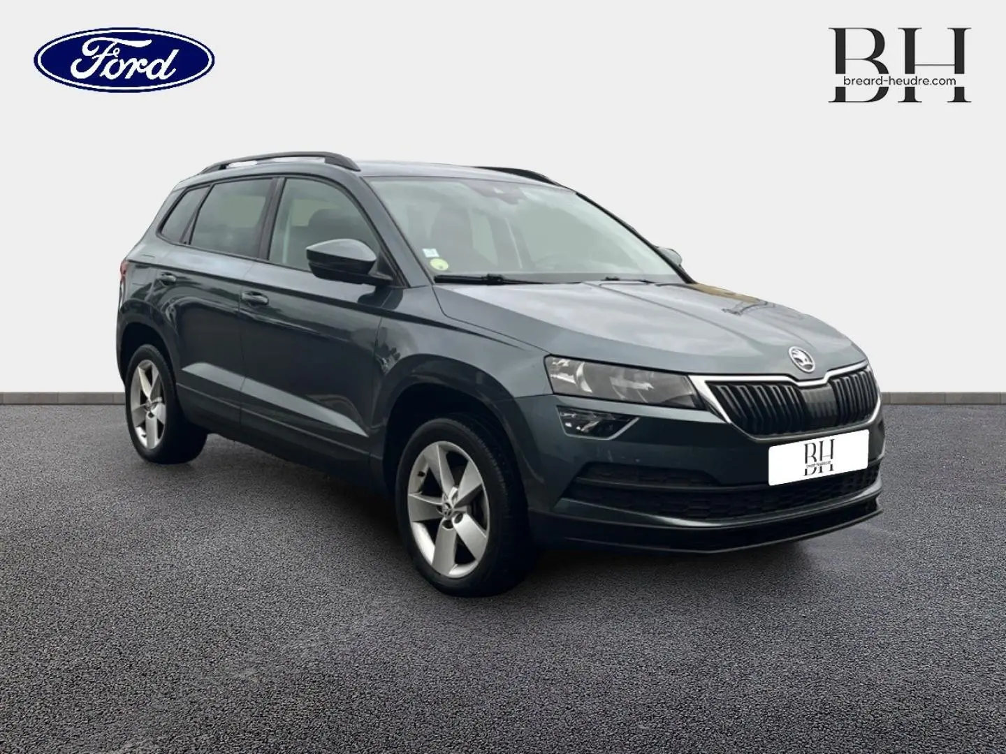 SUV Skoda Karoq gris Business vu en 3/4 avant droit, avec jantes alliage et calandre noire distinctive.