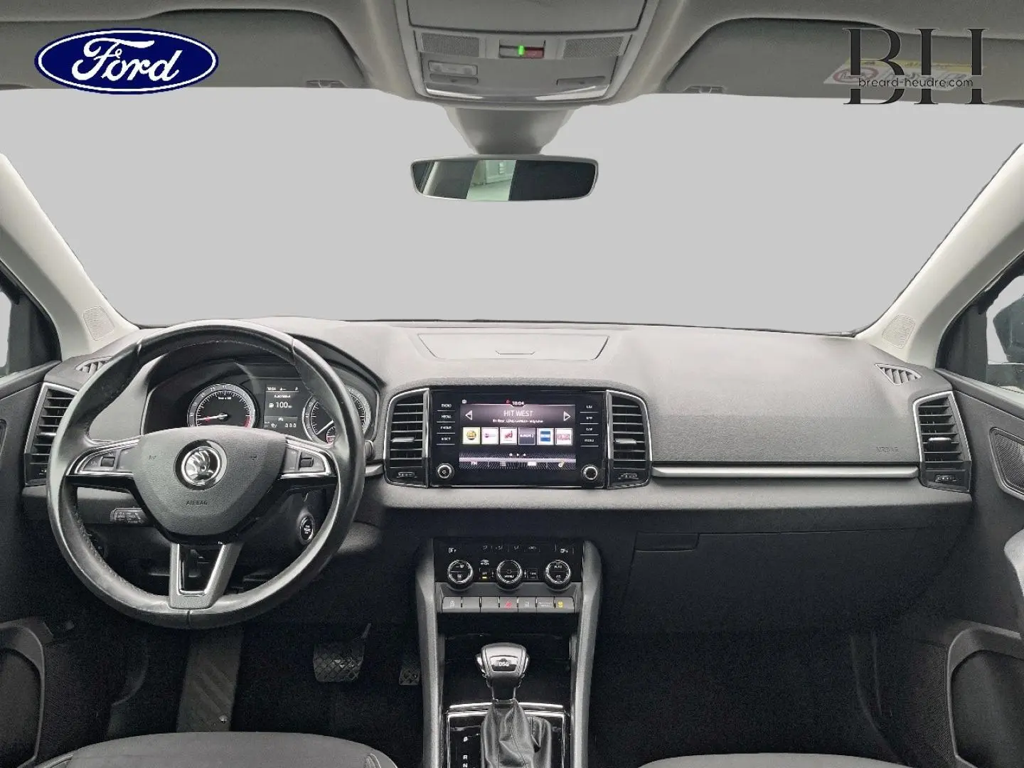 Vue intérieure avant du Skoda Karoq 2020, tableau de bord gris avec écran tactile et volant multifonction cuir.