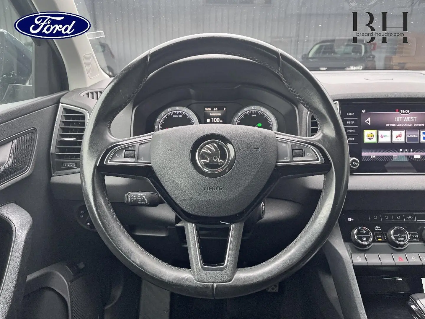 Vue intérieure centrée sur le volant cuir noir d'un Skoda Karoq 2020 avec tableau de bord et écran tactile visibles.