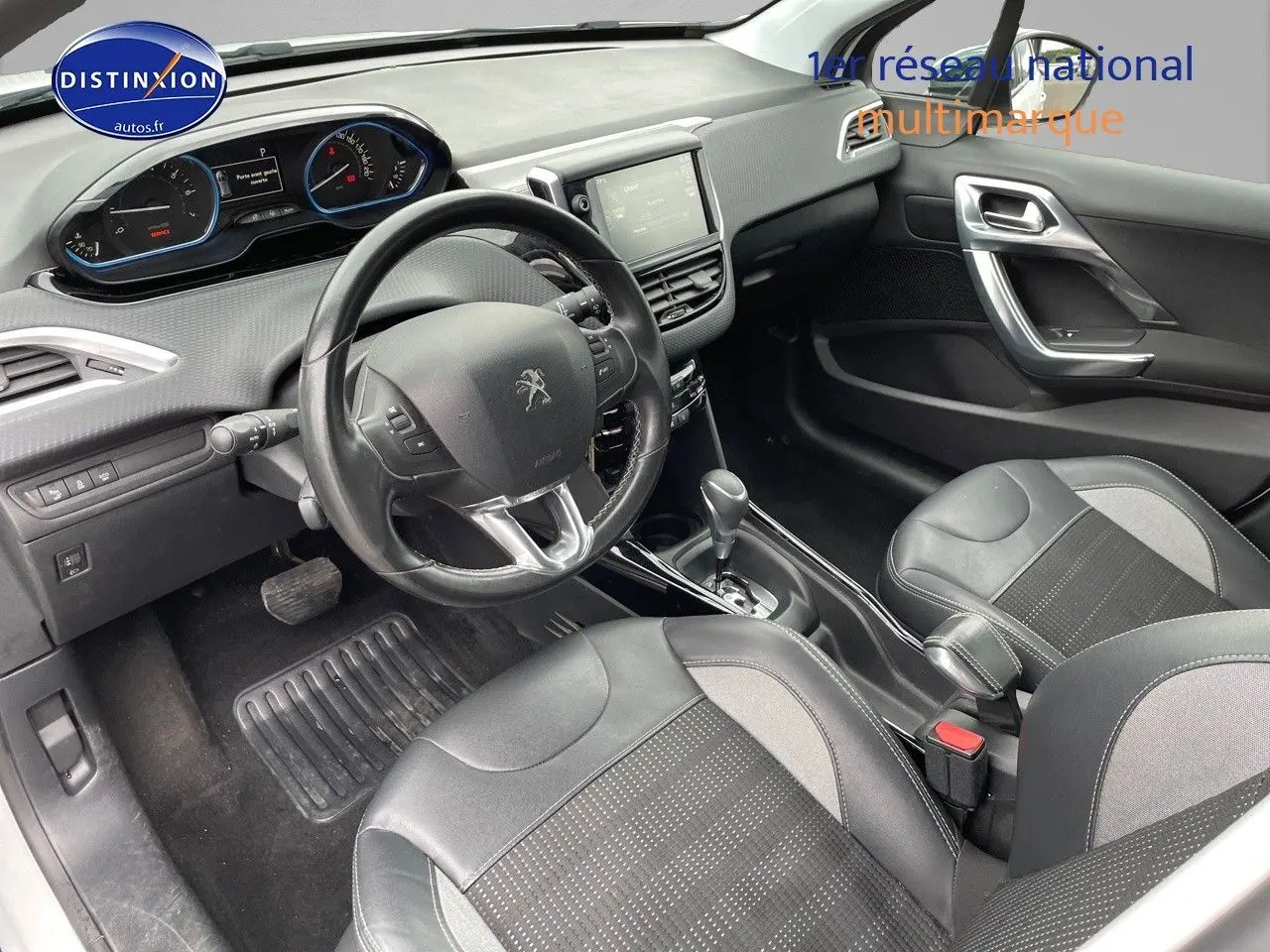 Vue intérieure côté conducteur du Peugeot 2008 blanc nacré de 2015, montrant le volant, tableau de bord et sièges en cuir noir.