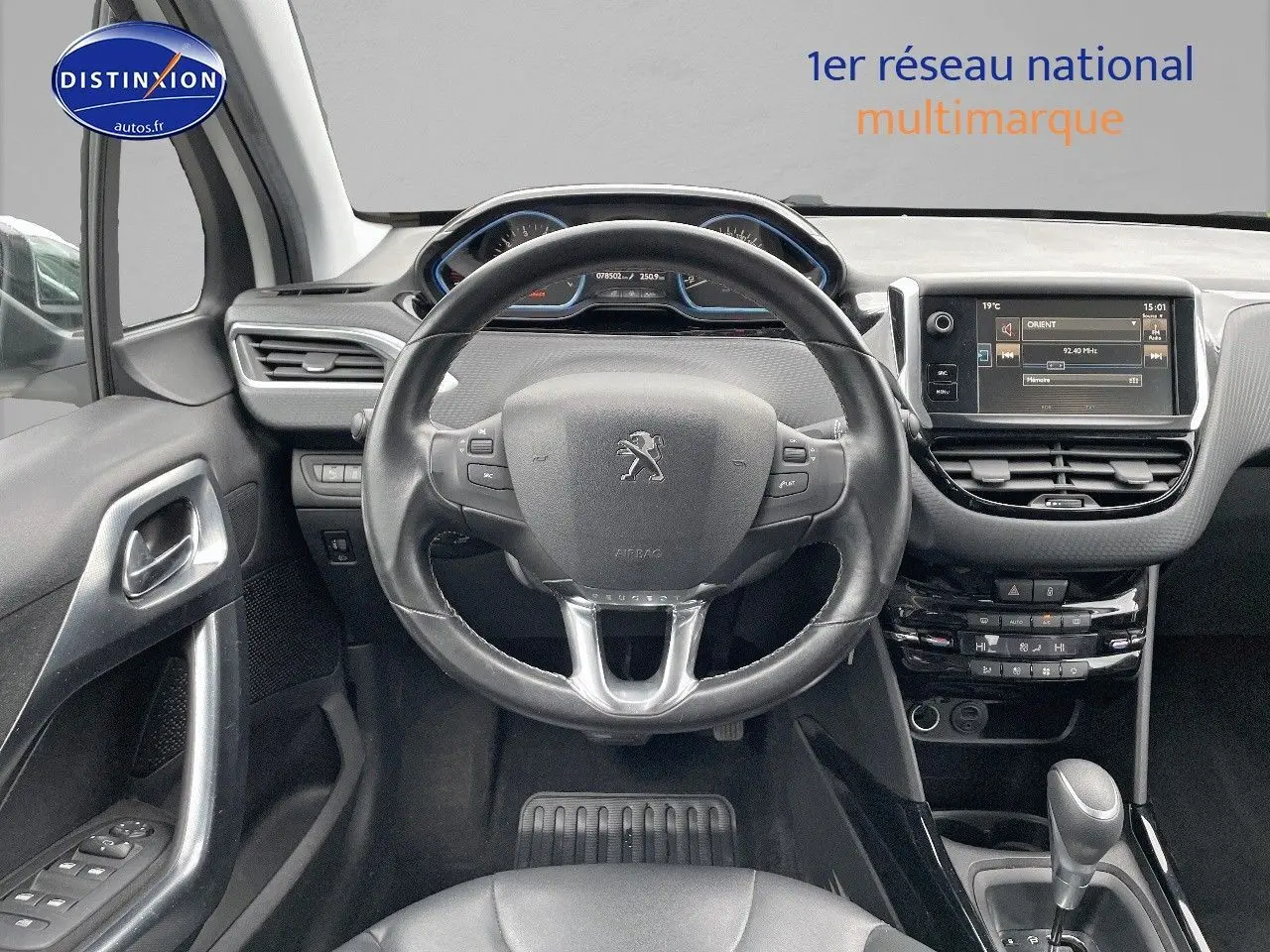 Vue intérieure centrée sur le volant cuir noir et le tableau de bord avec écran tactile du Peugeot 2008 blanc nacré 2015.