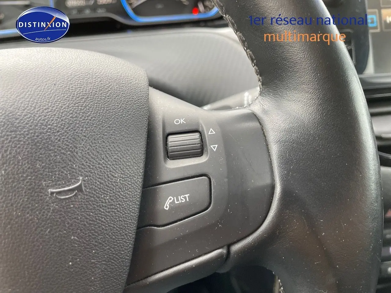 Gros plan sur les commandes au volant noir du Peugeot 2008 blanc nacré, mettant en valeur les boutons de gestion d'appel et menu.