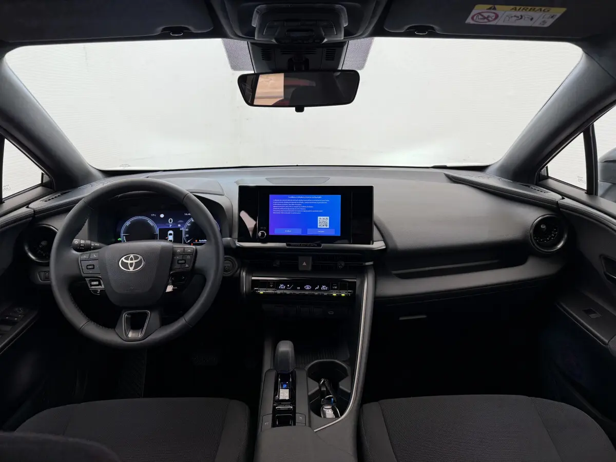 Intérieur noir du Toyota C-HR 1.8 Hybride 2024 vu de face, tableau de bord moderne avec écran tactile central.