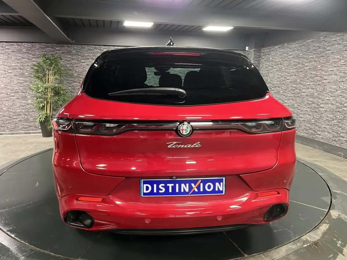 Vue arrière d'une Alfa Romeo Tonale rouge avec toit noir et feux arrière LED reliés par une barre lumineuse noire.