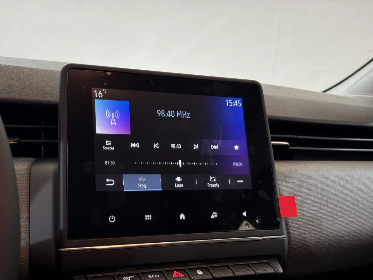 Écran tactile central allumé affichant la radio dans l'habitacle gris clair d'une Renault Clio 2025 Evolution Blue dCi