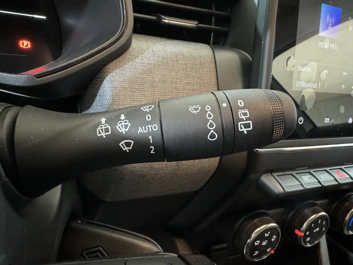 Gros plan sur la commande d’essuie-glace noire dans l’habitacle gris clair de la Renault Clio Evolution Blue dCi 100 2025.
