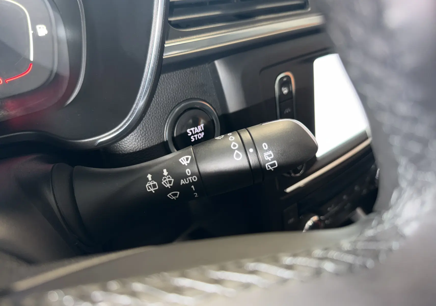 Gros plan sur la commande d’essuie-glace du Renault Kadjar gris, avec bouton start/stop et tableau de bord partiellement visible.