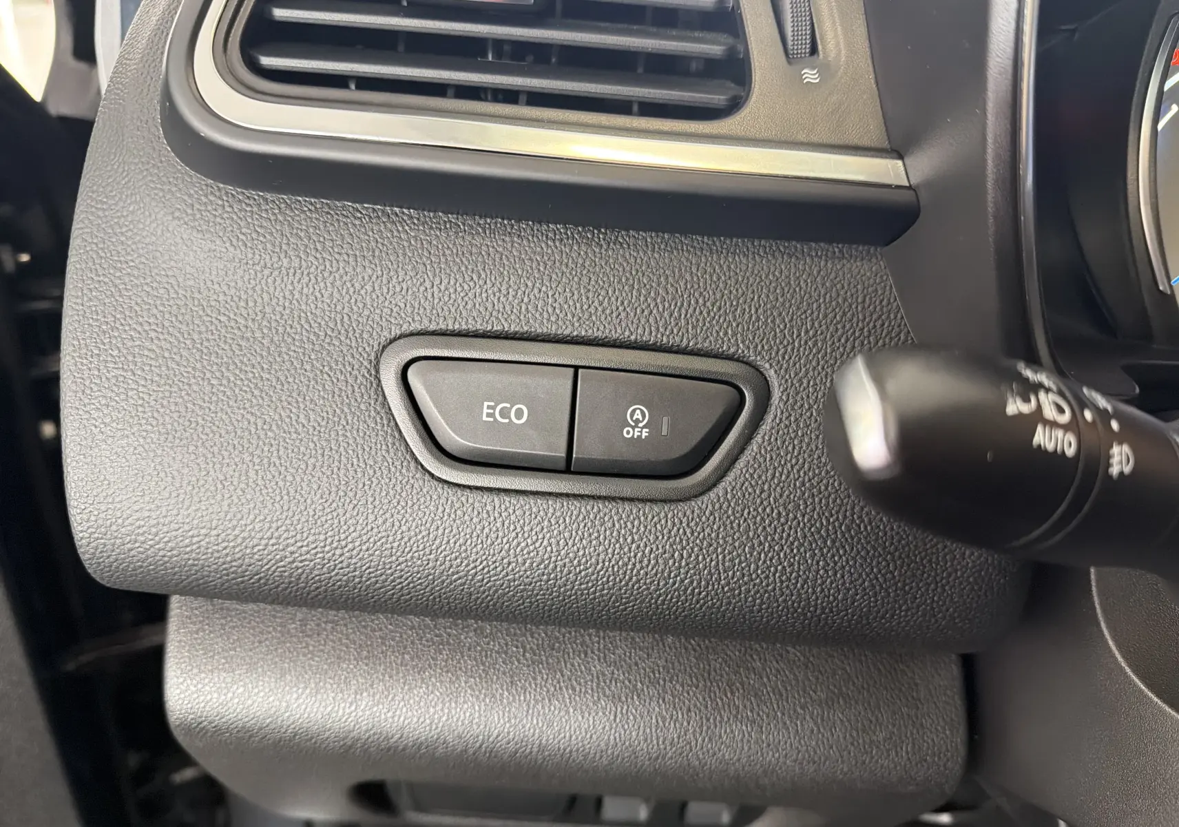 Détail intérieur du tableau de bord côté gauche du Renault Kadjar gris, avec boutons ECO et arrêt auto start-stop.