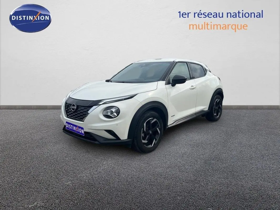 Nissan Juke blanc en 3/4 avant droit, avec jantes aluminium noires et calandre noire distinctive.