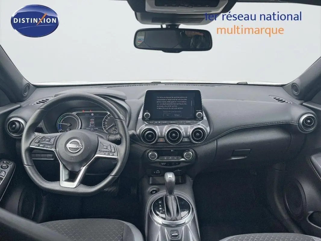 Vue intérieure frontale du tableau de bord noir du Nissan Juke 2024 avec écran tactile central et volant cuir multifonction.