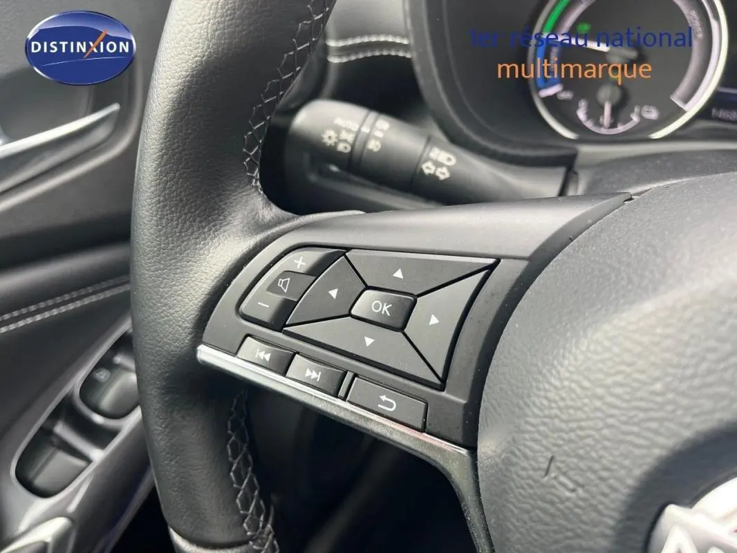 Gros plan sur les commandes multimédia au volant cuir noir du Nissan Juke blanc, version 2024, côté gauche.