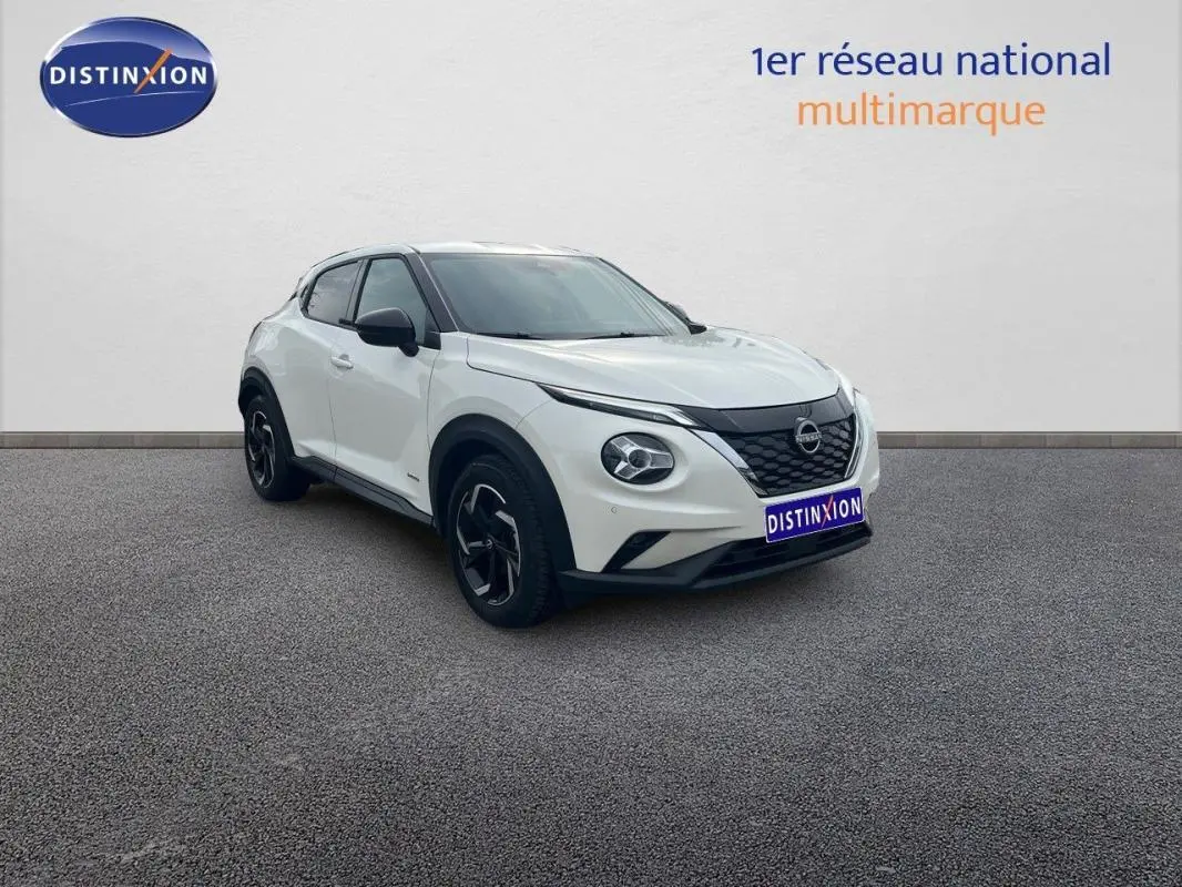 Nissan Juke blanc en 3/4 avant droit, avec calandre noire et jantes aluminium distinctives.