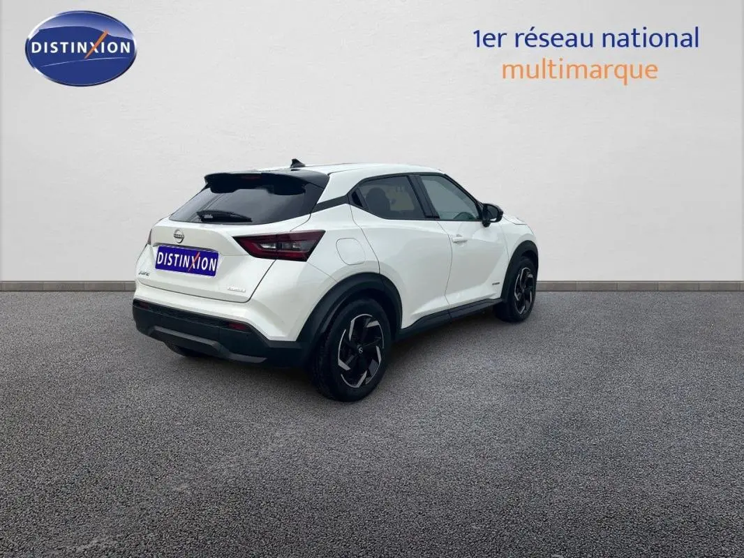 Vue 3/4 arrière droite d'un Nissan Juke blanc 2024 avec jantes aluminium et vitres teintées.
