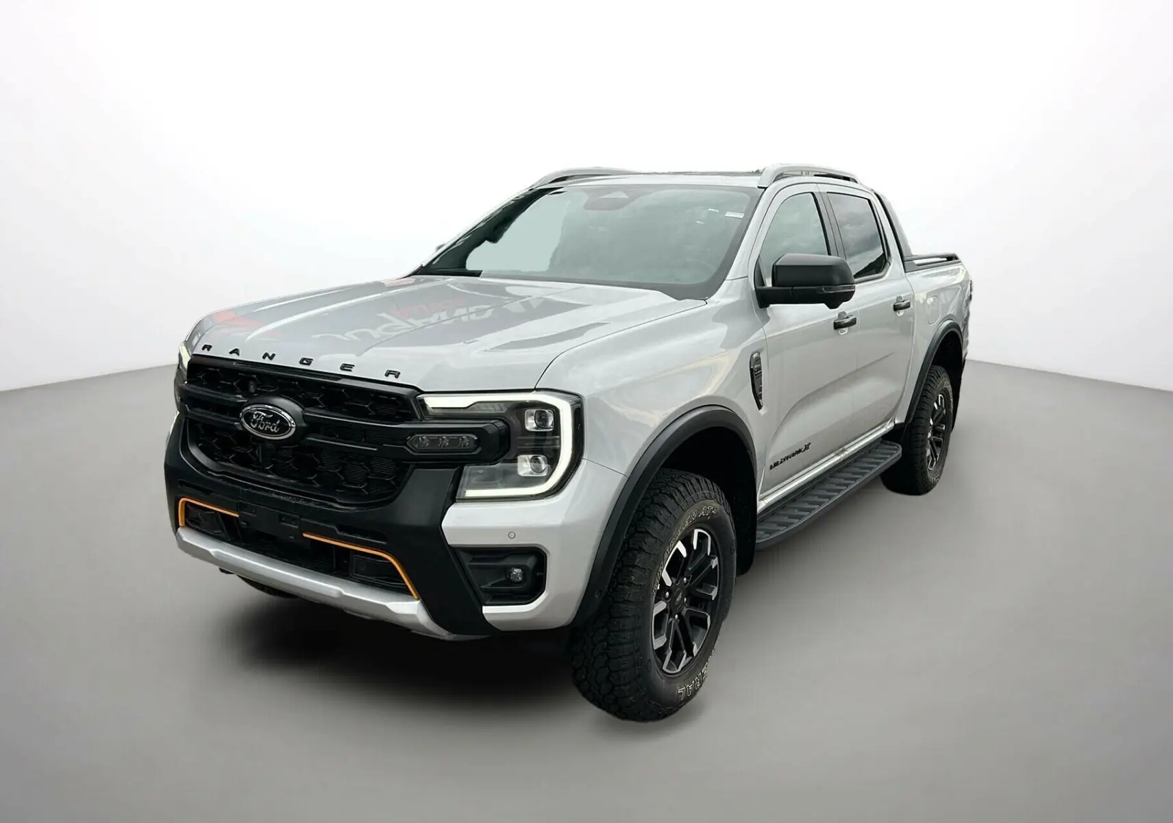 Ford Ranger 2026 gris iconic en 3/4 avant droit avec calandre noire et détails orange sur pare-chocs.