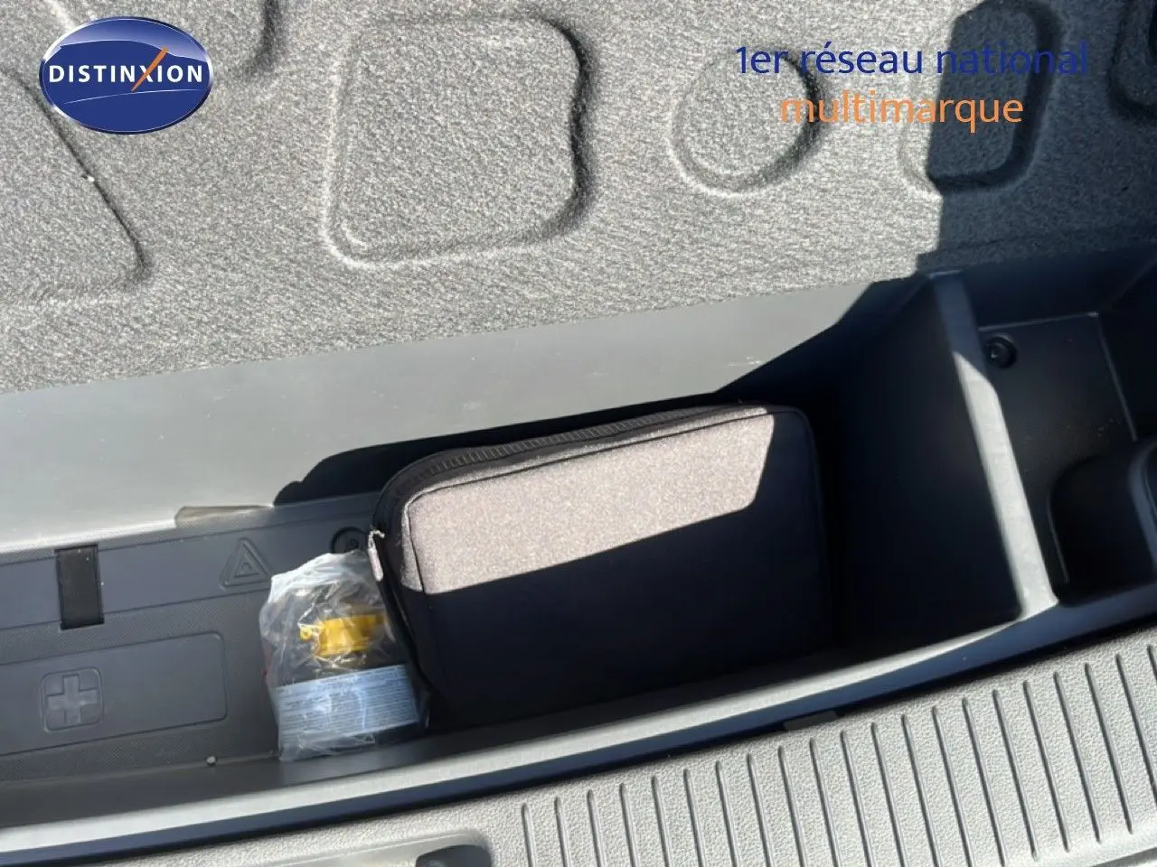 Coffre ouvert de la Hyundai i30 SW 2023 en Sunset Red Metal, montrant un rangement avec trousse et équipement de sécurité.