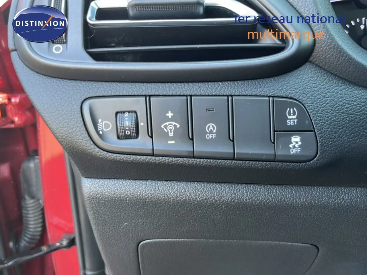 Vue rapprochée du tableau de bord côté gauche avec commandes d’éclairage et aides à la conduite sur Hyundai i30 SW rouge.
