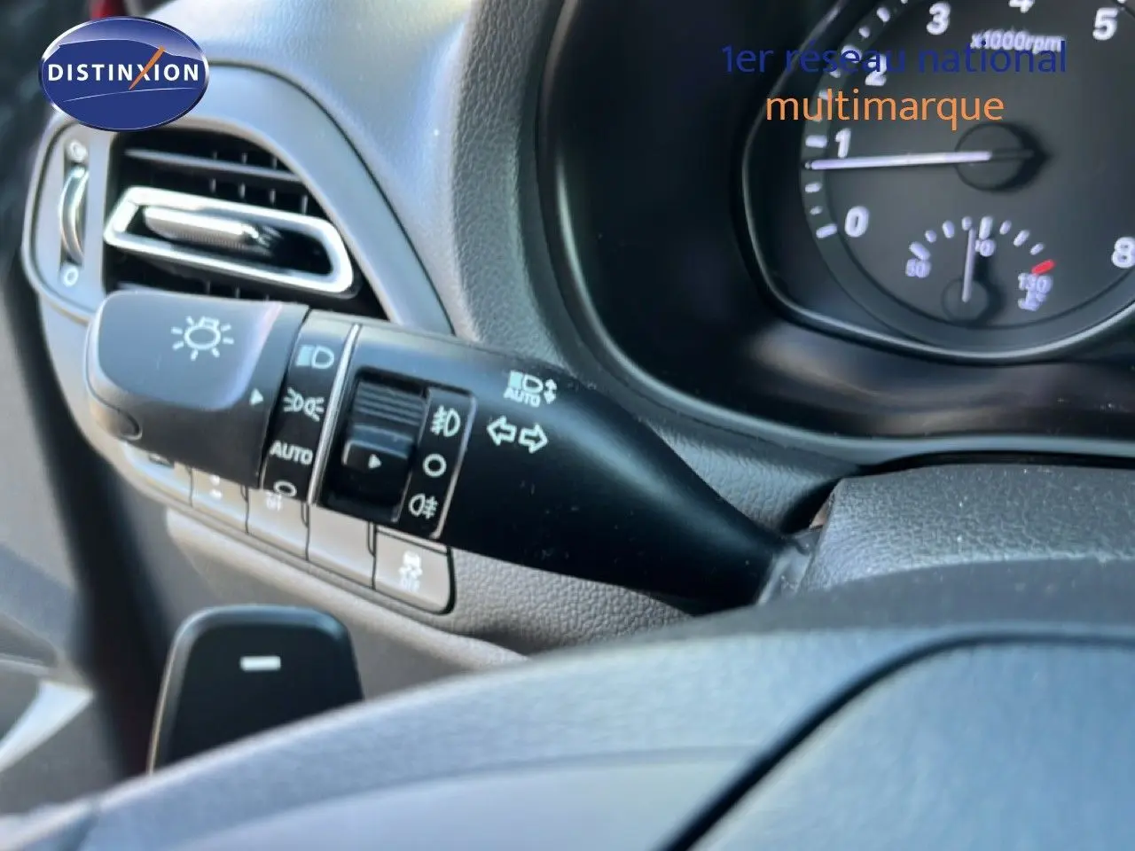 Gros plan sur la commande des feux et clignotants côté gauche du tableau de bord d’une Hyundai i30 SW rouge.