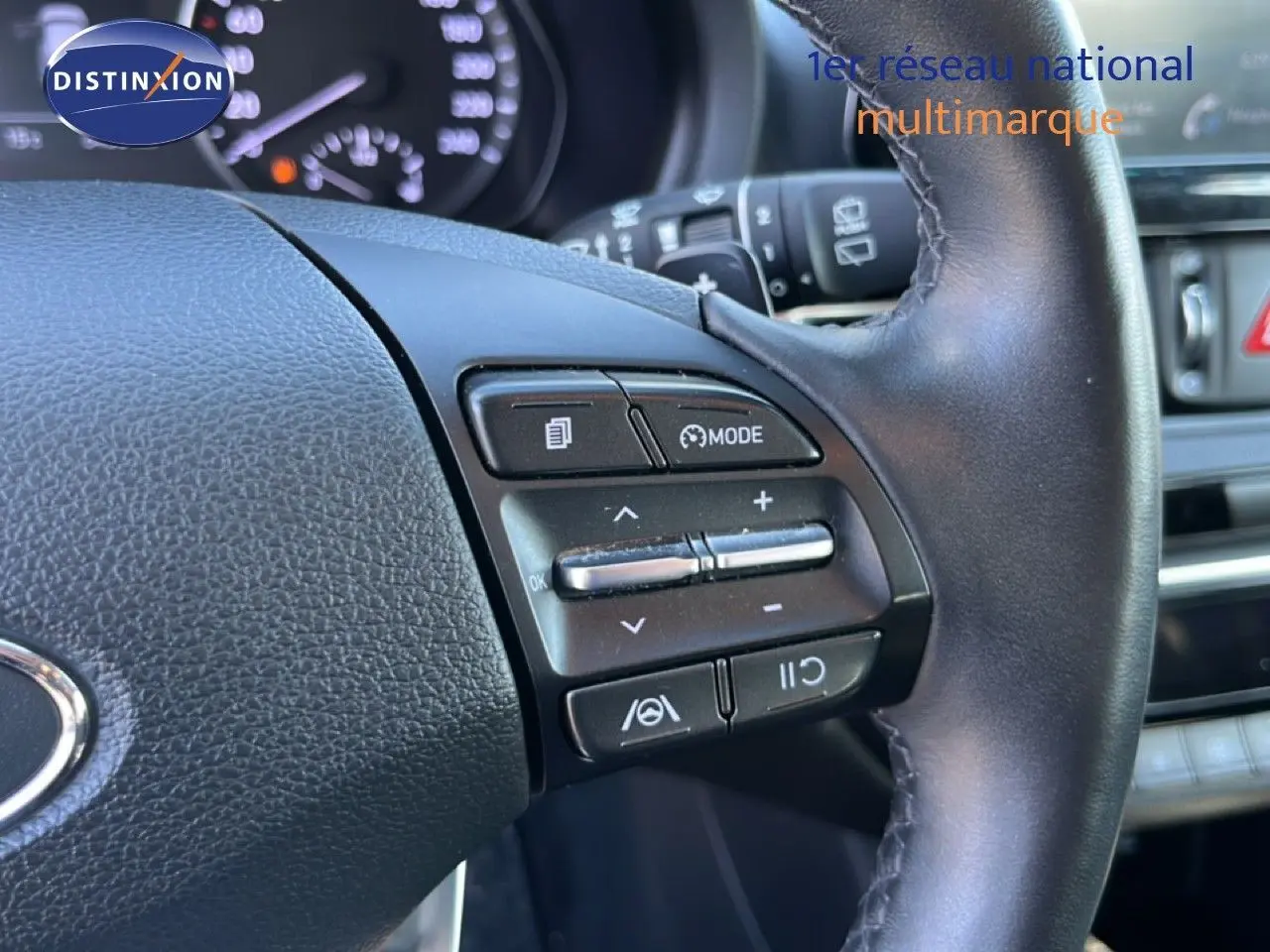 Gros plan sur les commandes au volant à droite du Hyundai i30 SW 2023, intérieur noir avec tableau de bord en arrière-plan.
