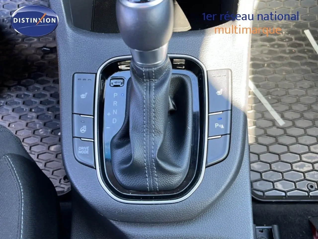 Gros plan sur la console centrale de la Hyundai i30 SW 2023 avec levier de vitesses automatique et boutons de sièges chauffants.