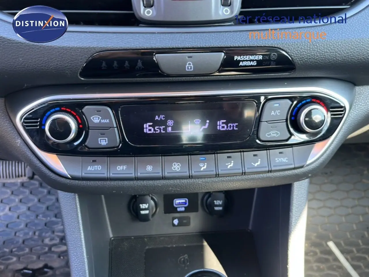 Vue rapprochée de la console centrale de la Hyundai i30 SW 2023, avec commandes climatisation digitale et ports USB et 12V.