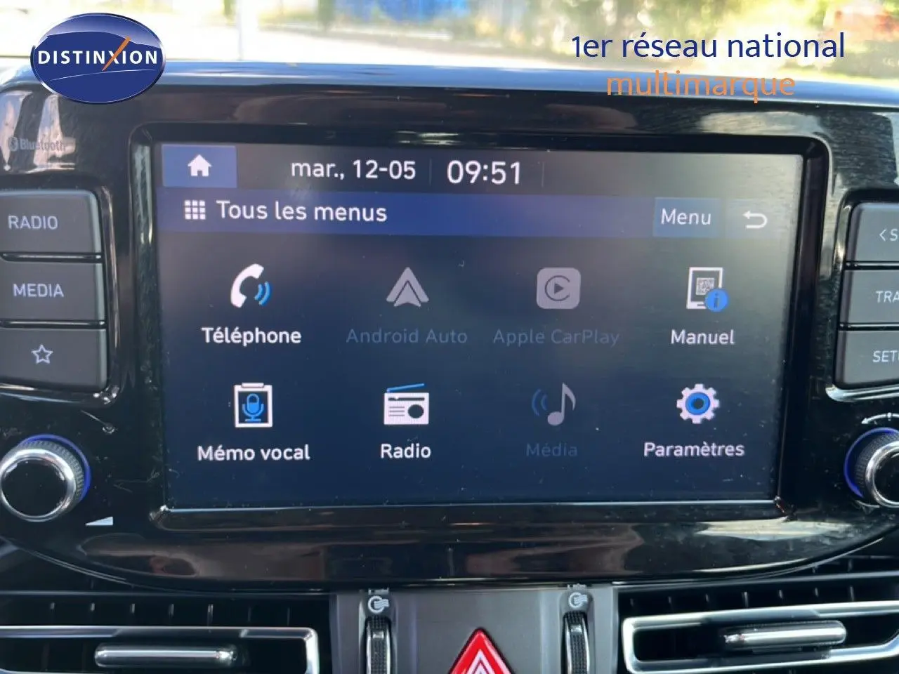 Écran tactile central de la Hyundai i30 SW 2023 affichant les menus téléphone, radio et paramètres, avec commandes autour.