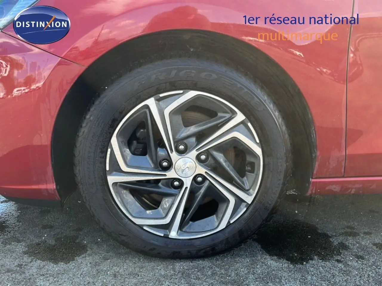 Gros plan sur la roue arrière droite d'une Hyundai i30 SW 2023 rouge Sunset Red Metal avec jante alliage bicolore.