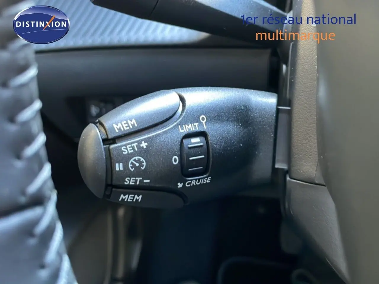 Gros plan sur la commande de régulateur de vitesse au volant d'une Peugeot 208 HYBRID 110CH noire.