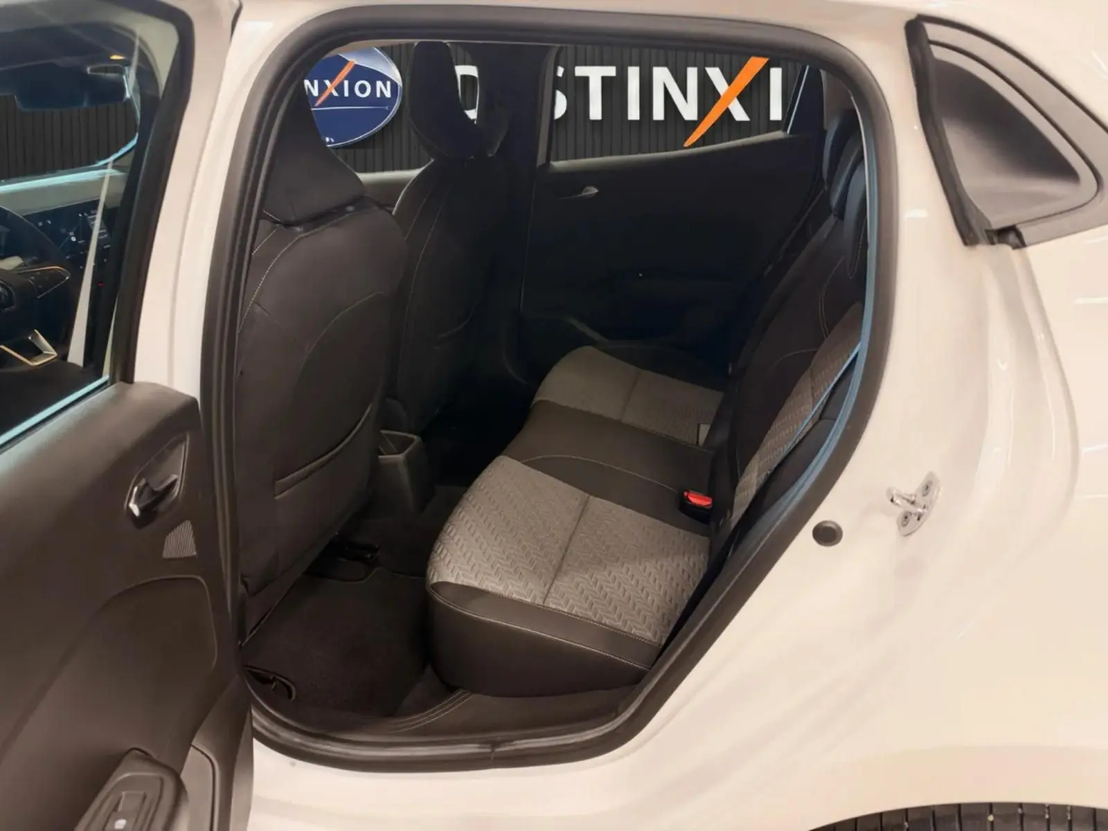 Vue côté droit arrière de l'intérieur d'une Renault Clio V blanche, montrant les sièges arrière en tissu gris et noir.