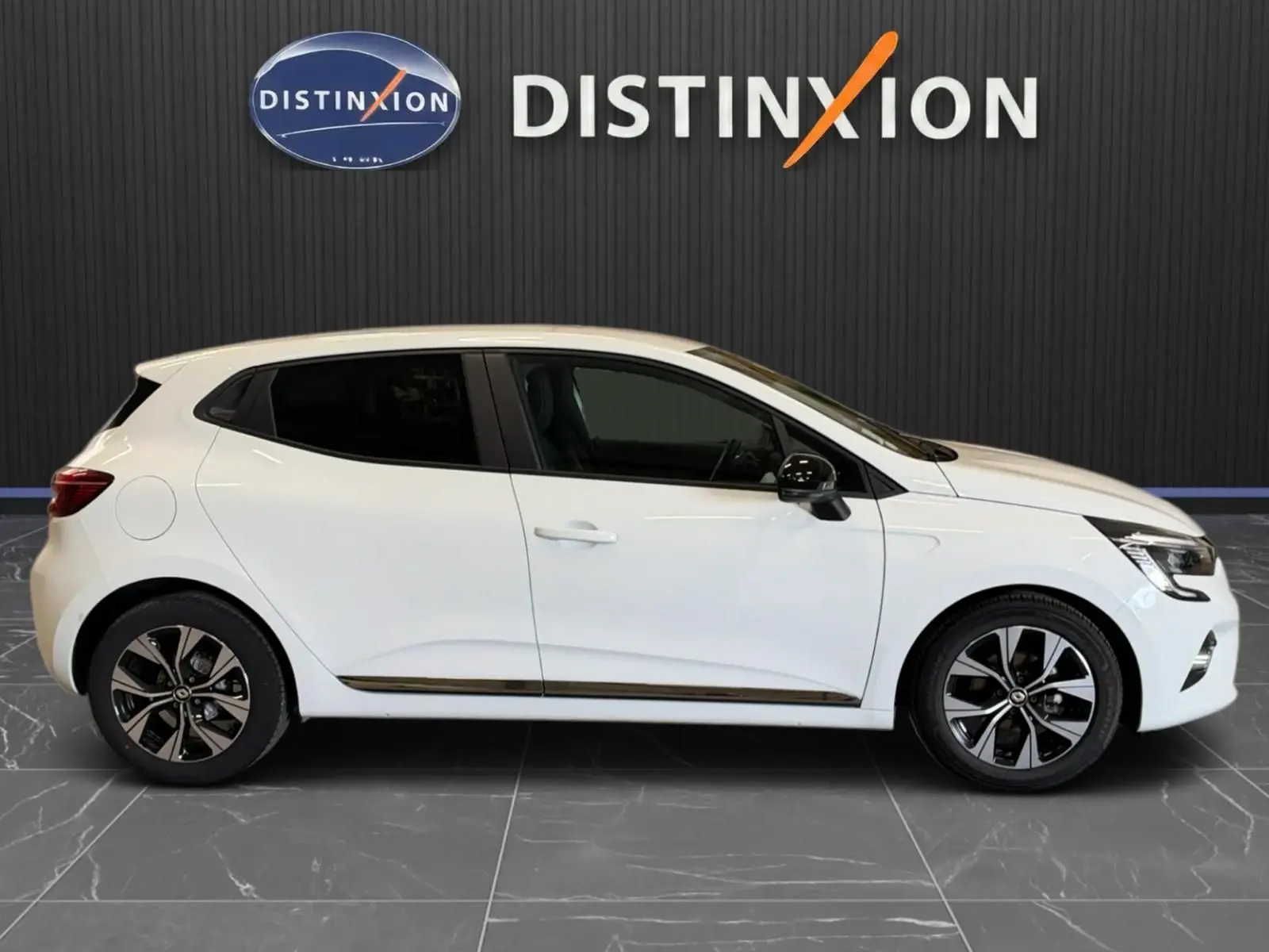 Profil droit d'une Renault Clio V blanche 5 portes de 2023, avec jantes bi-ton et vitres teintées.