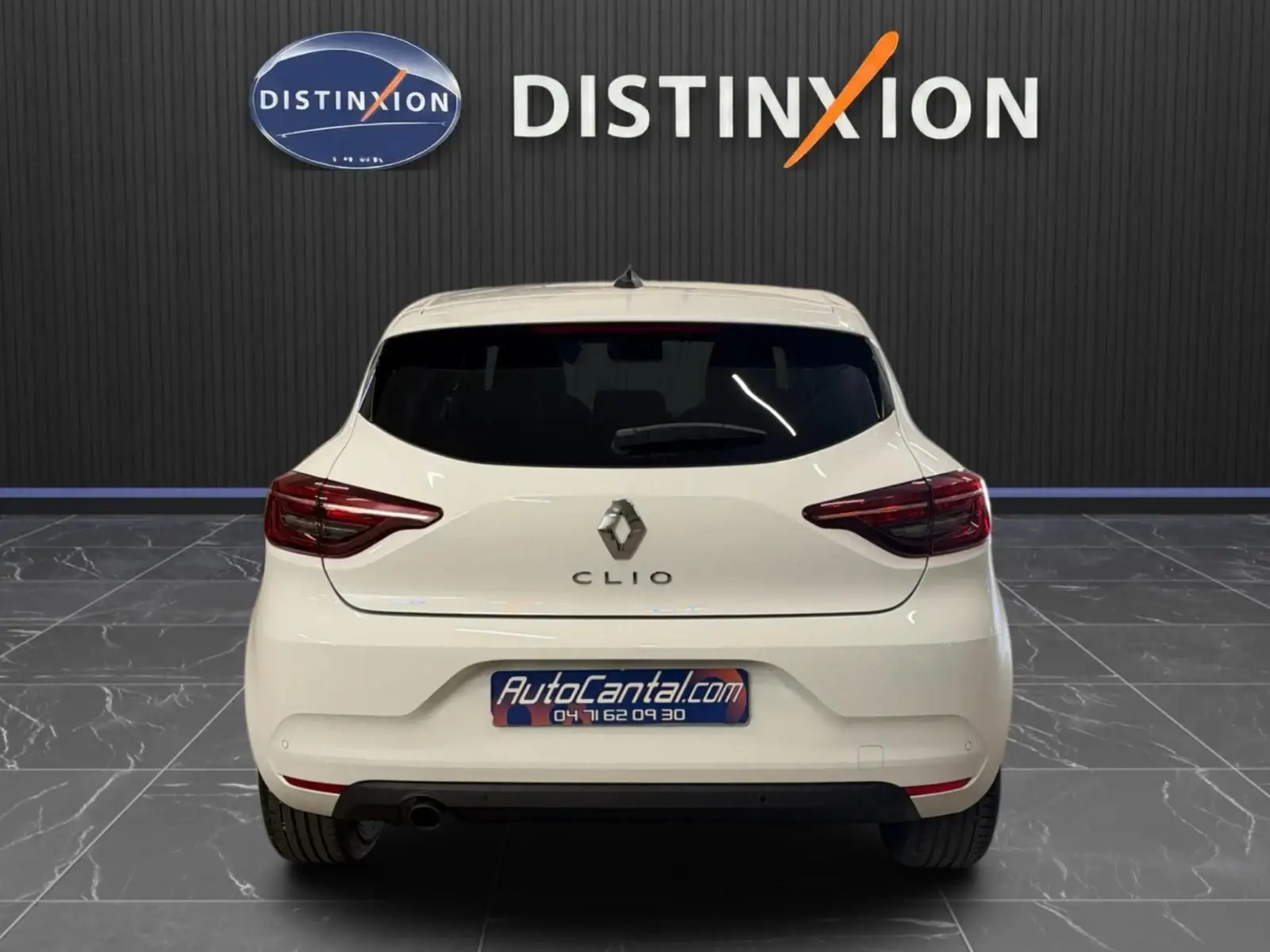 Vue arrière d'une Renault Clio V blanche, avec feux LED et logo distinctif sur fond intérieur showroom.